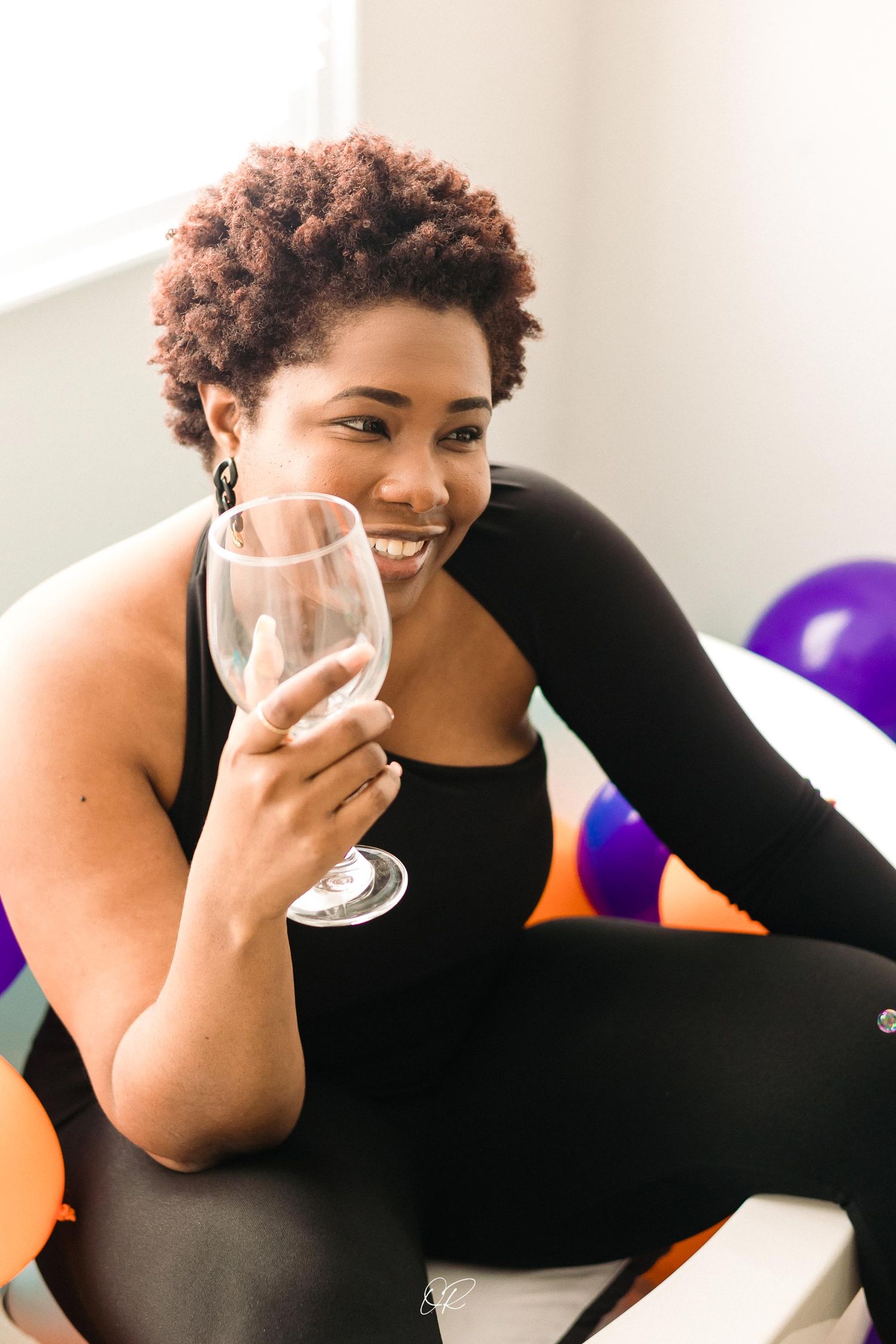 A joyful celebration scene with colorful balloons and a wine glass in hand.
