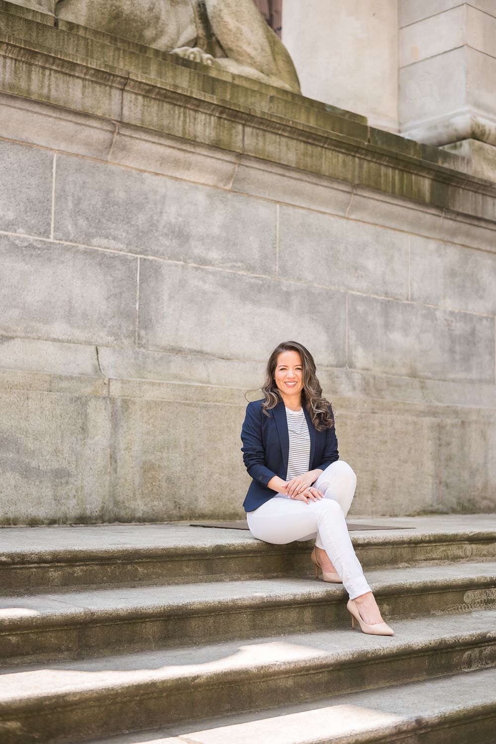 A businesswoman sits outside on a staircase wearing a navy blazer. Photo taken in Vancouver, BC.