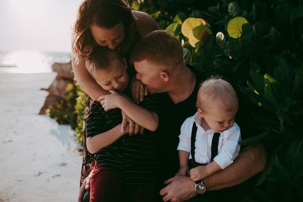 An intimate family moment captured outdoors near yellow flowers. Sarasota Family Photographer. Lido Beach Photographer.