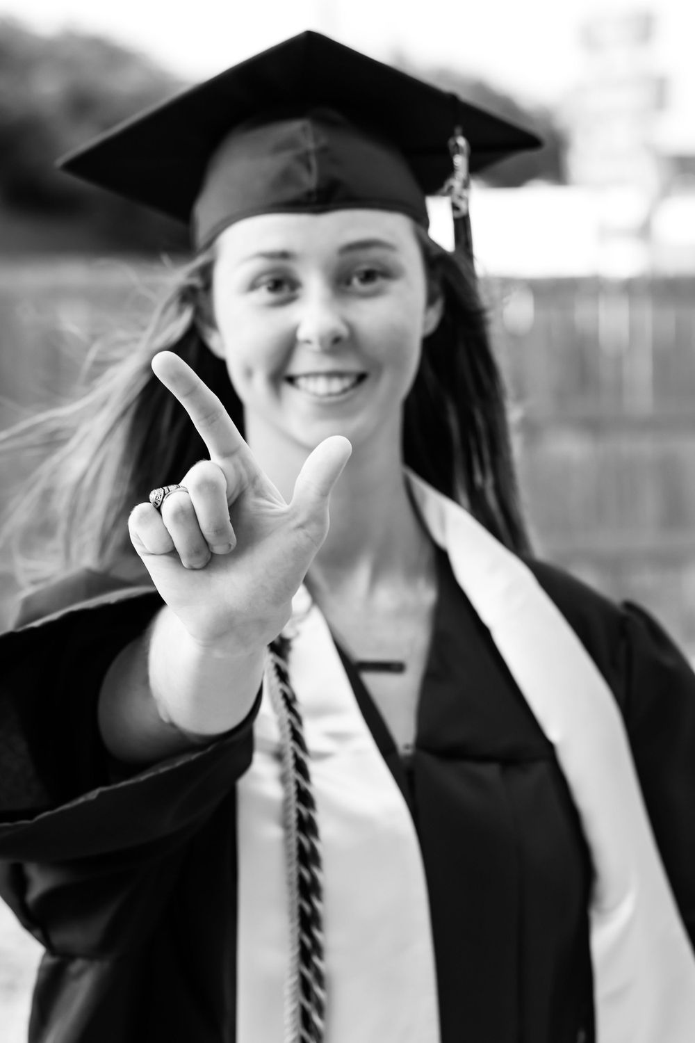 Graduate poses in cap and gown with thumbs up gestures in black and white photo series.