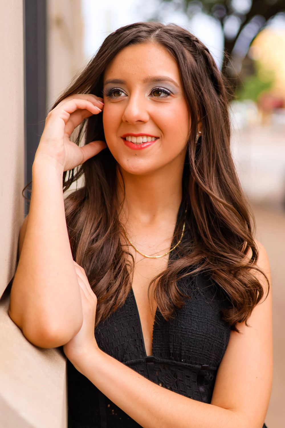 Portrait of a brunette in a black dress with long wavy hair and natural makeup.