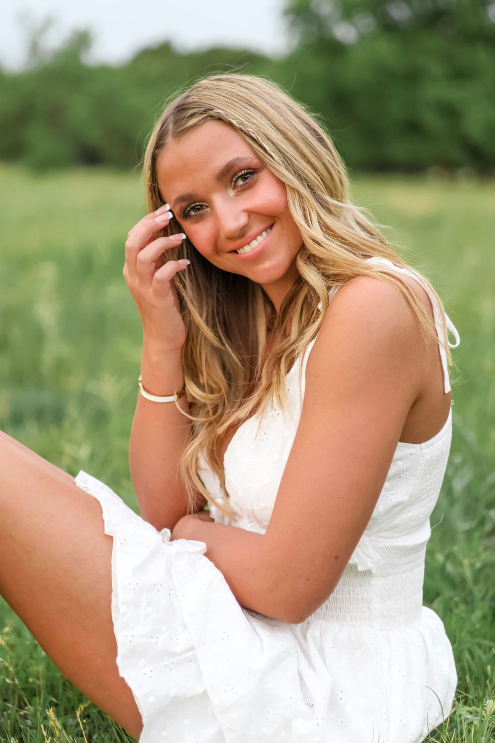 Portrait series in grassy field featuring subject in white summer dress.