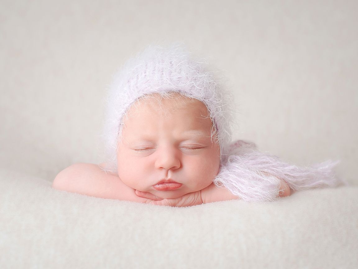 newborn baby girl in lilac bonnet in newborn session