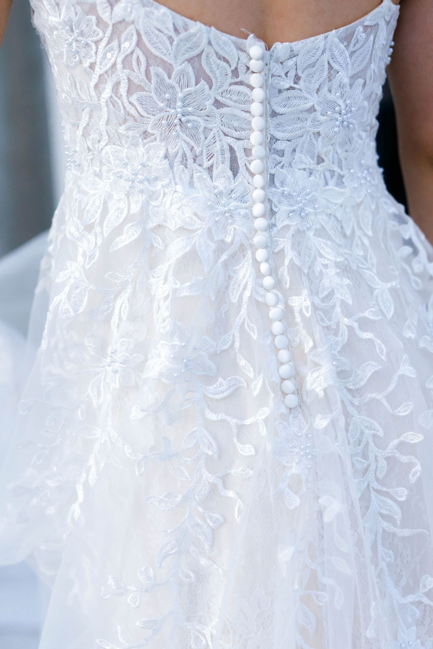 The image shows the back of a white wedding dress with intricate lace detailing.