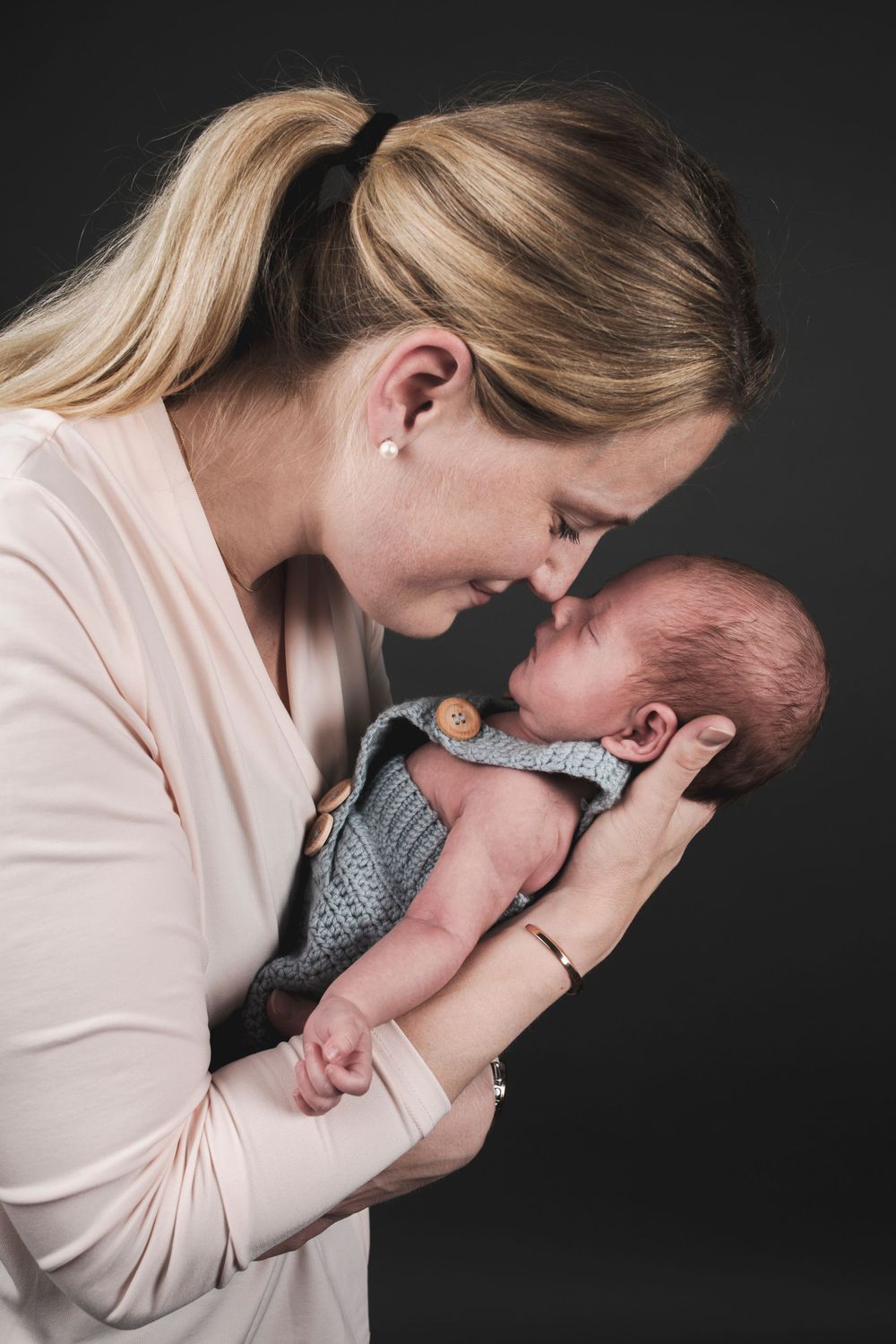 Tender moment between parent and newborn baby in studio portrait setting.