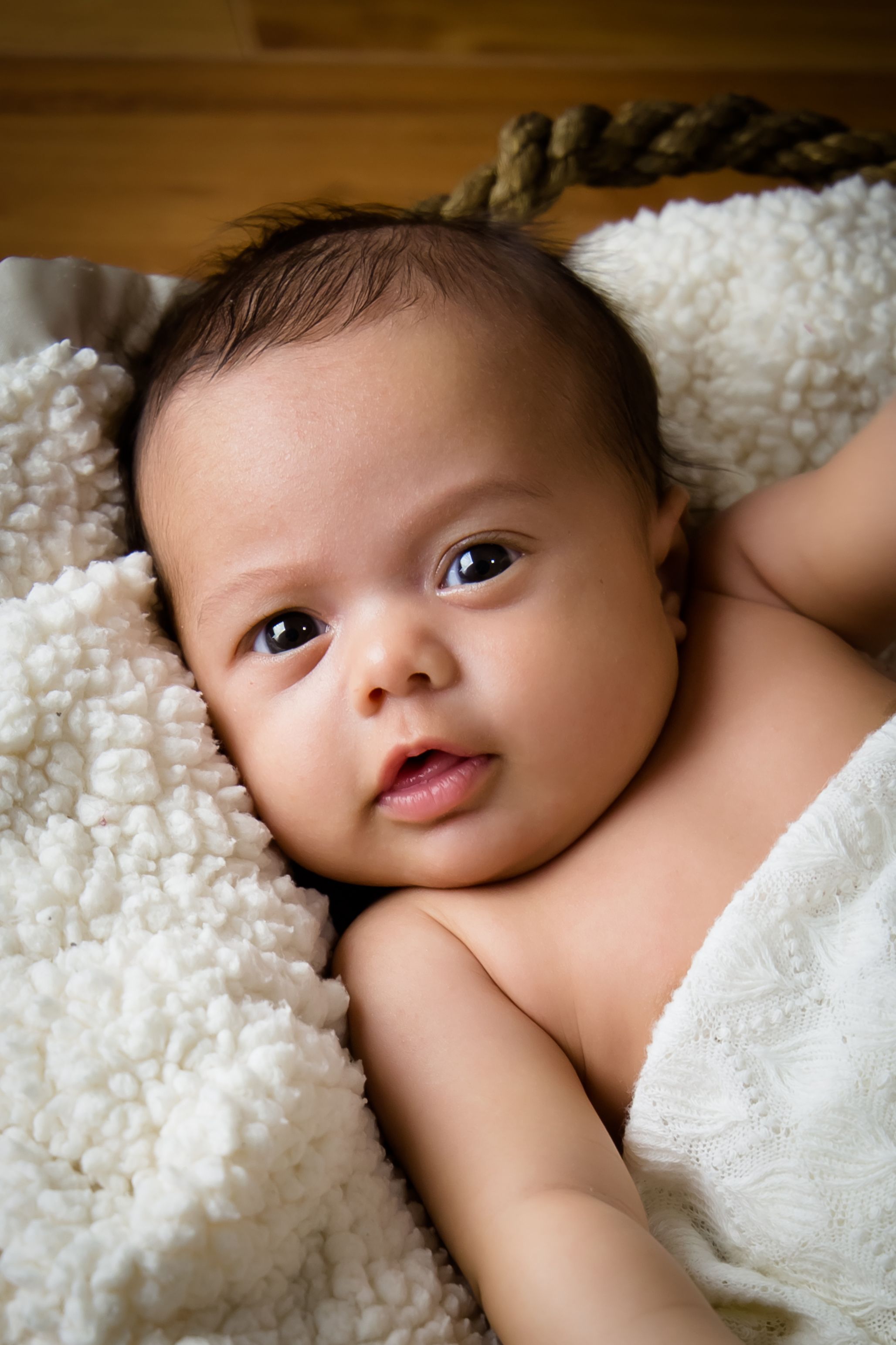 Close-up portrait of baby lying on white textured blanket.