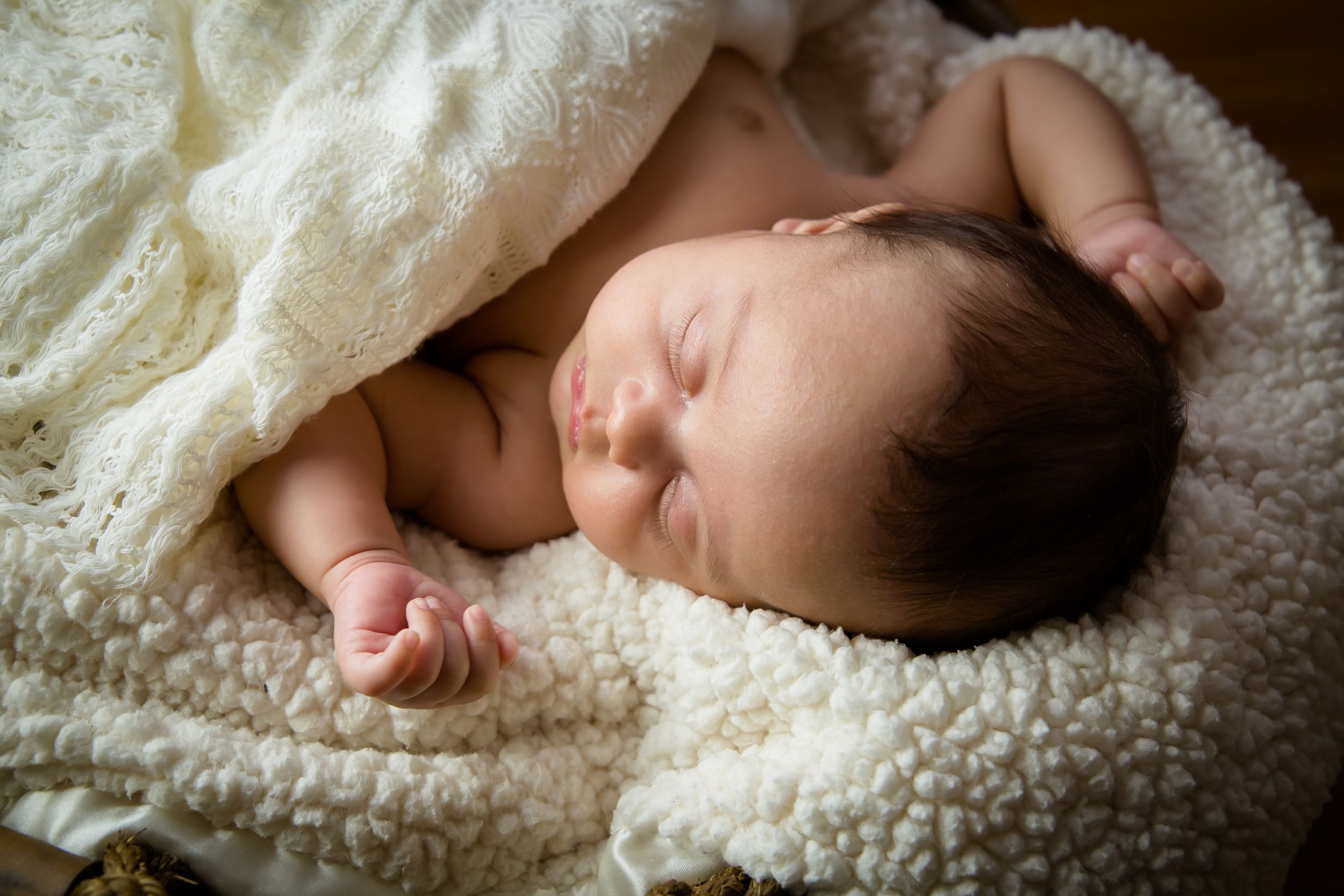 Sleeping newborn photography series on soft white blanket.