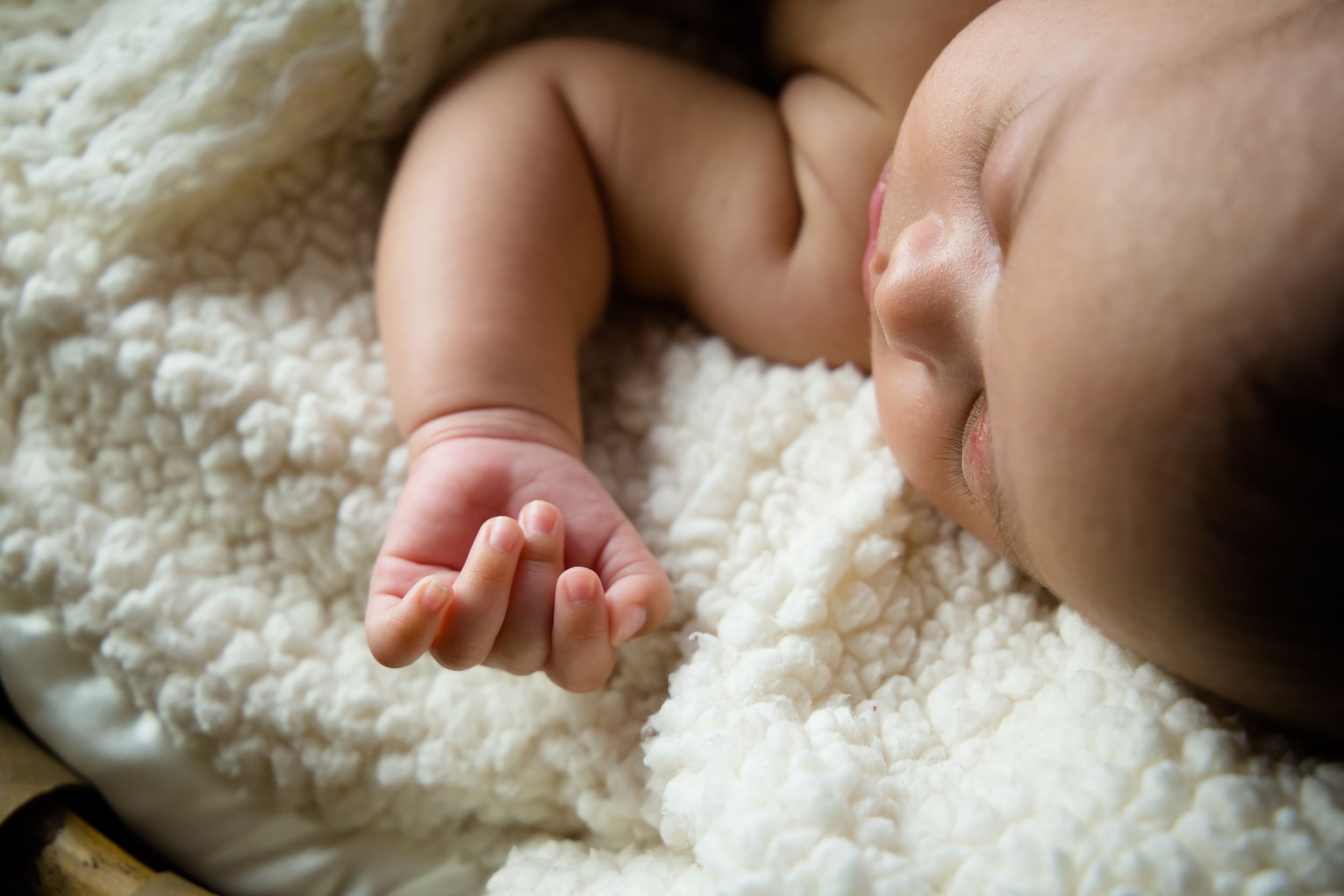 Artistic macro shots of newborn details on white textured fabric.