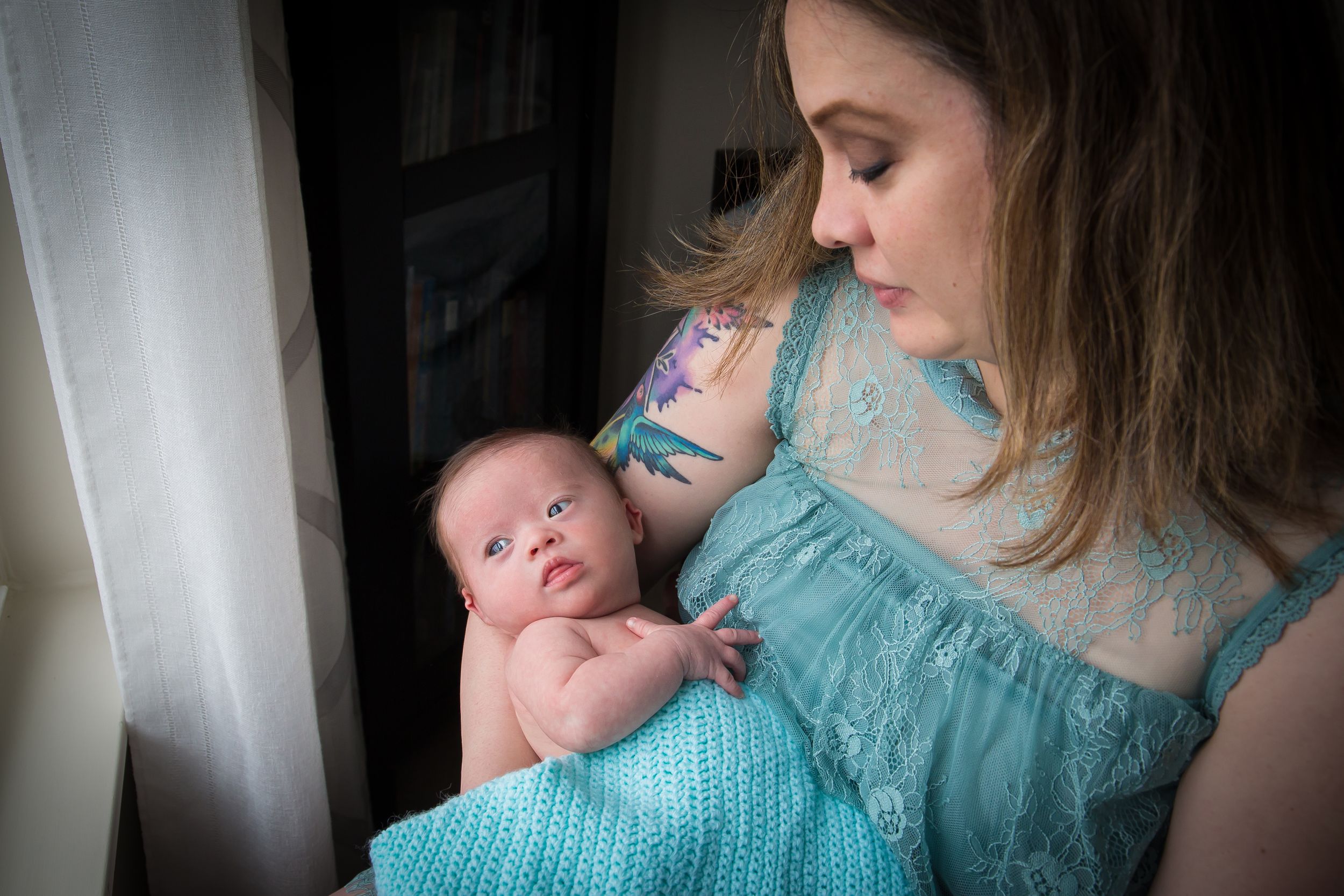 A tender moment captured as a baby rests against someone in a turquoise top.
