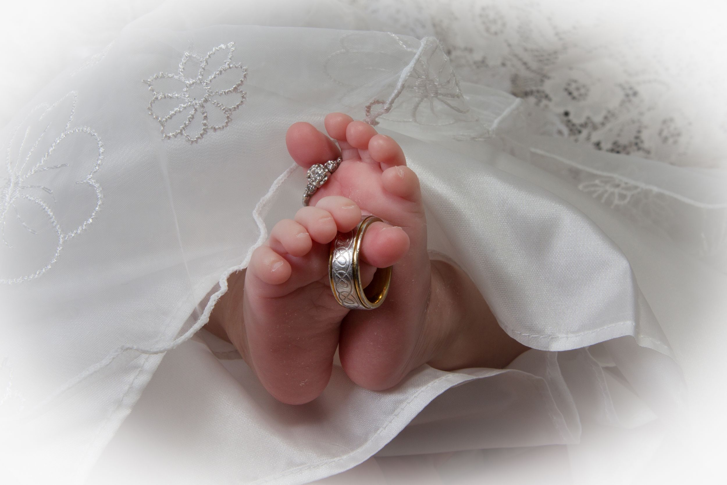 Close-up details of tiny feet in white christening garments.