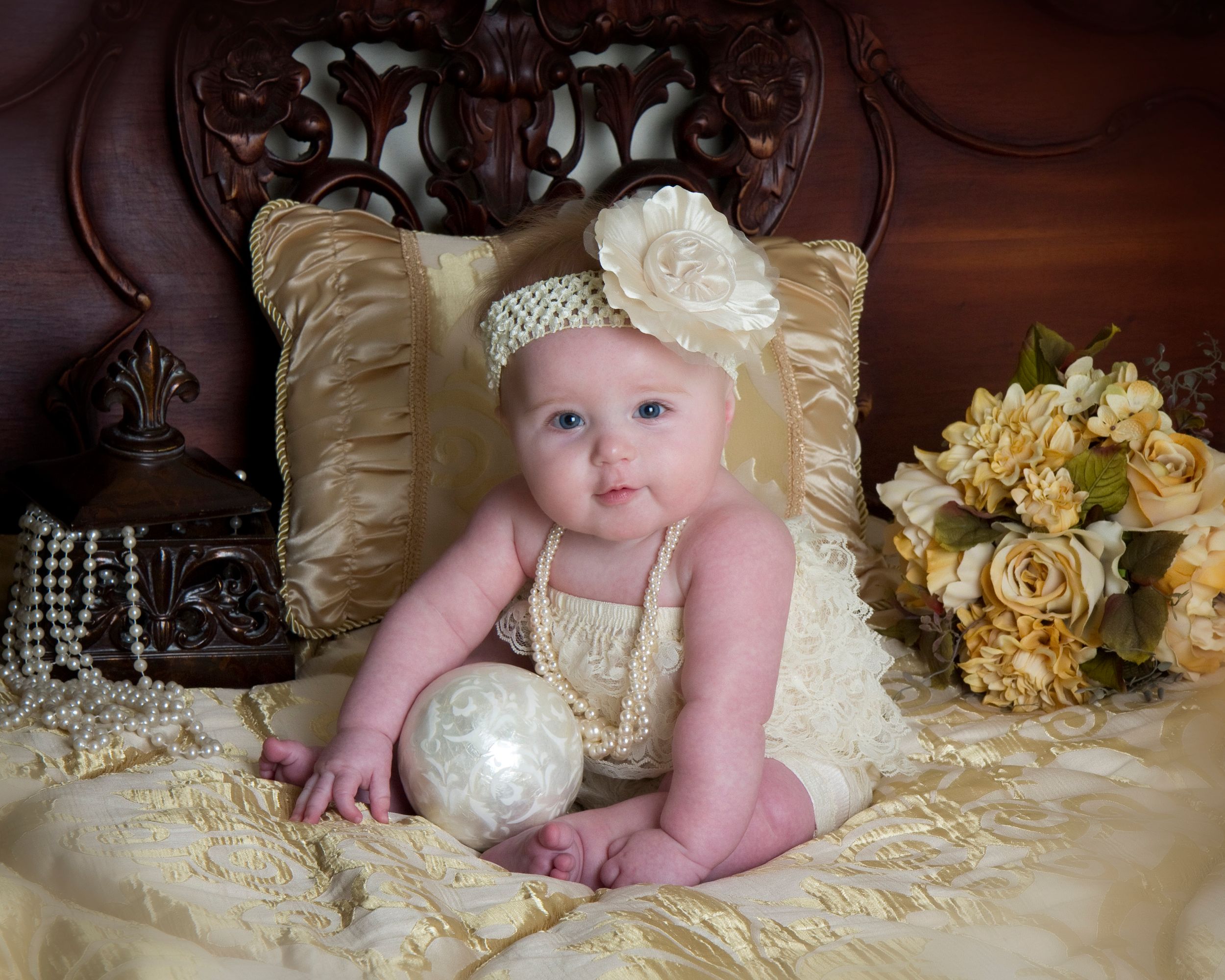 Baby in vintage-style portrait with cream pillows and yellow roses.
