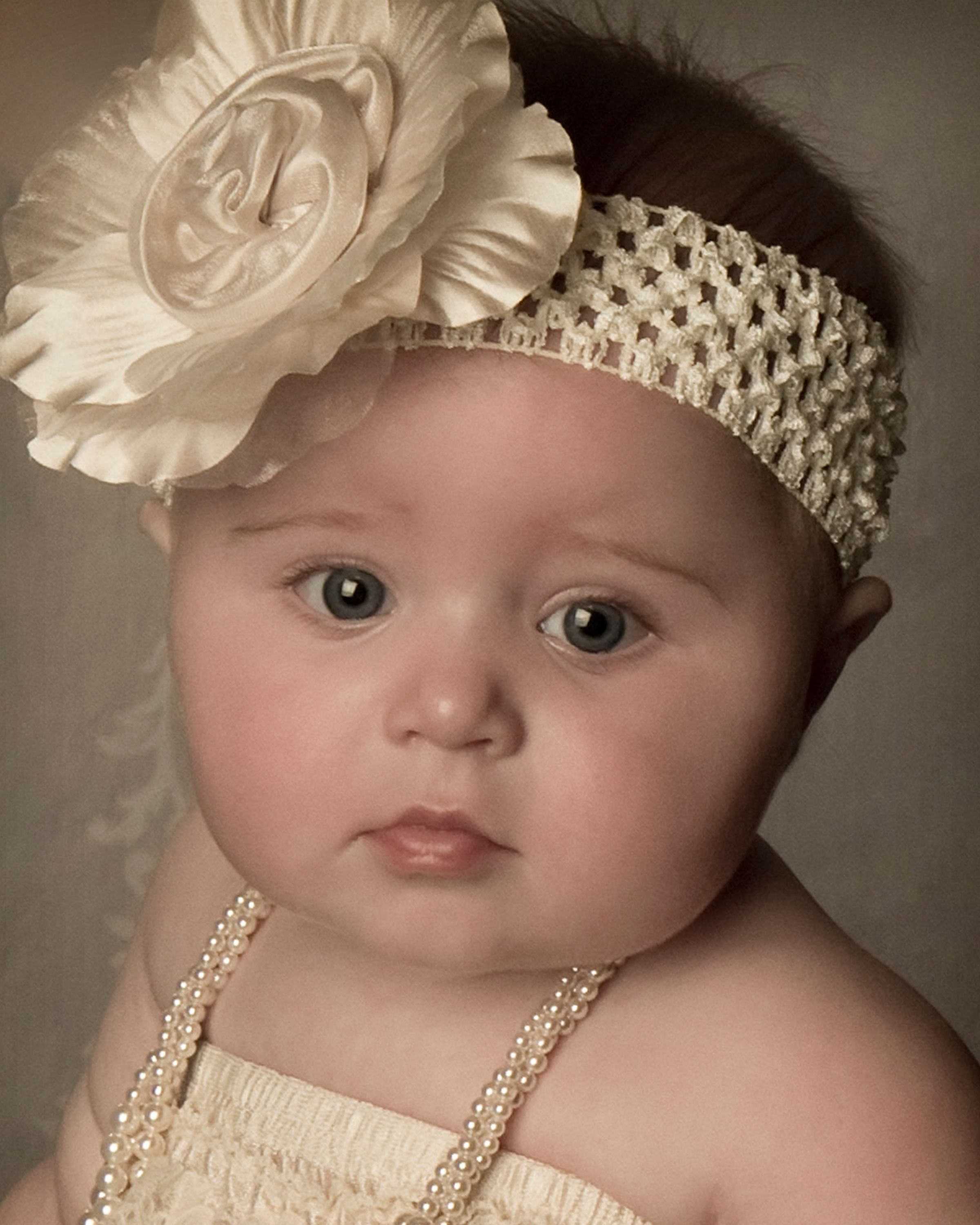 Close-up portrait with cream floral headband and pearl straps.
