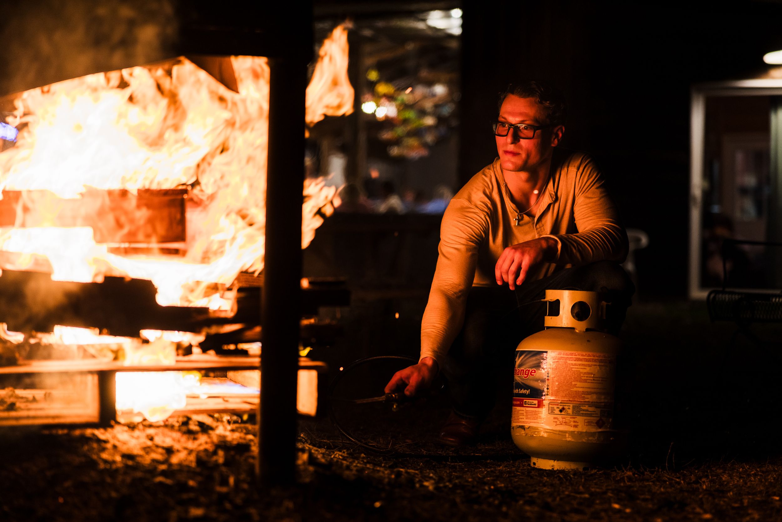 Warm firelight illuminates an outdoor evening gathering.