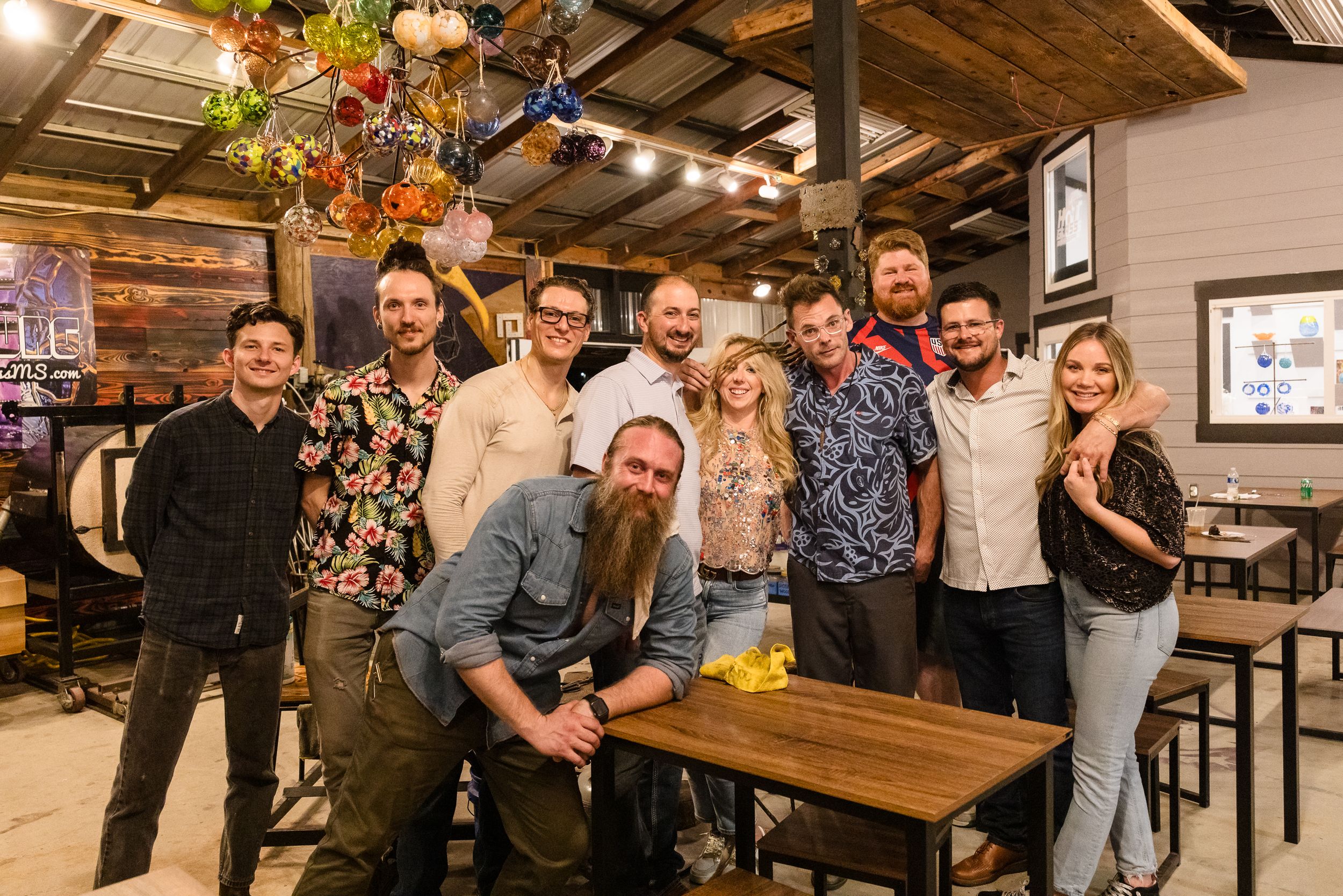 People gathering in a rustic indoor venue with wooden tables and festive lighting.