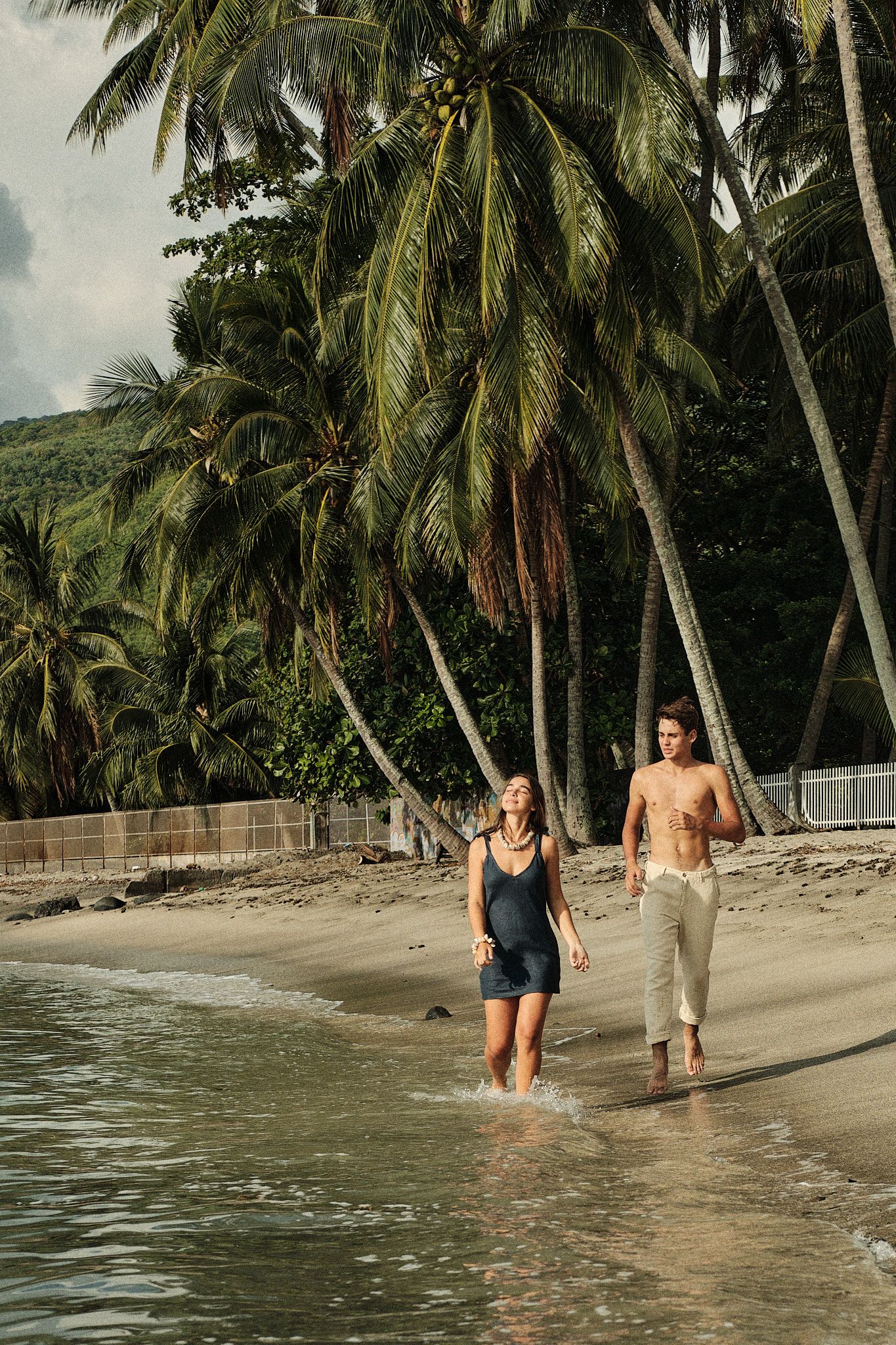 Jeune couple marchant le long d'une plage de sable blanc à Paea. Shooting photo pour le Hine Magazine.