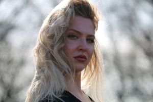 A portrait of someone with platinum blonde wavy hair and red lipstick in soft natural lighting.