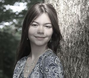Close-up portrait with natural lighting showing someone wearing a paisley dress and earrings.