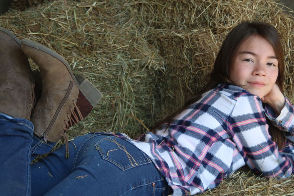 Someone resting in casual wear on hay bales inside a rustic barn setting.