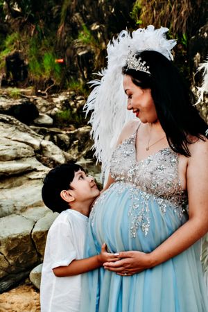 A maternity moment captured in a blue sparkly dress with natural scenery.