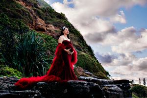 A figure in red poses dramatically against coastal cliffs and cloudy skies.