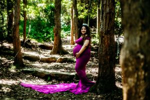 Ethereal forest photoshoot with flowing purple fabric among tall pine trees.