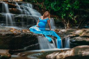 Maternity photo shoot at cascading waterfall with flowing blue dress.