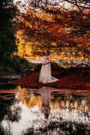 Dreamy maternity photos reflected in still water during golden hour.