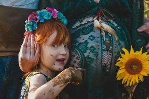 Woman wearing floral crown with bright sunflower accent in artistic portrait.