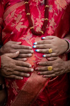 Close-up of hands with blue nail polish against red floral fabric.
