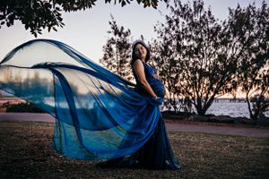 Elegant blue gown billowing in the wind during sunset silhouette photoshoot.