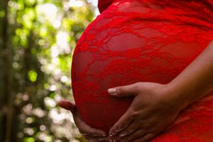 Close-up of a maternity photo showing a red dress against natural lighting.