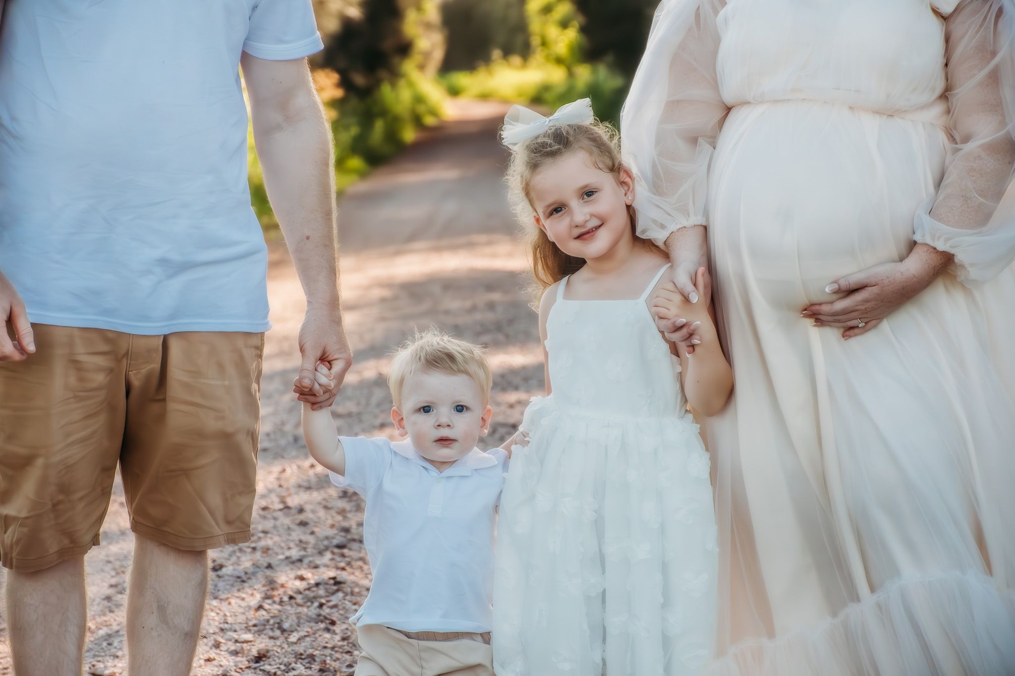 Family group wearing white and khaki clothing photographed from waist down.