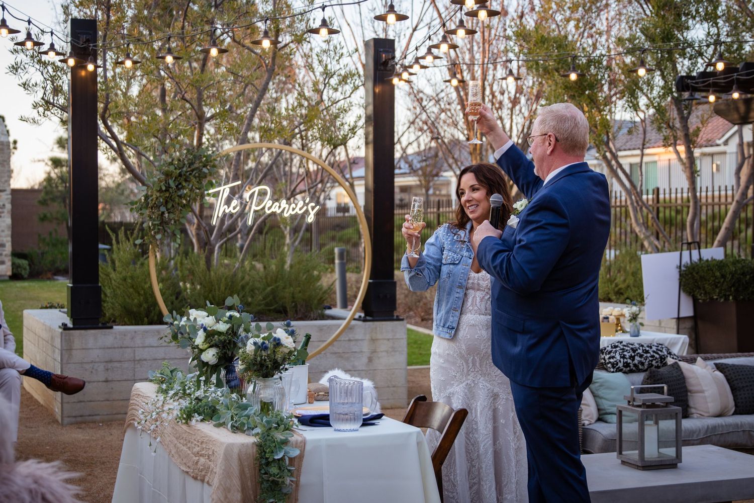Elegant outdoor wedding reception setup with white chairs and floral decorations.