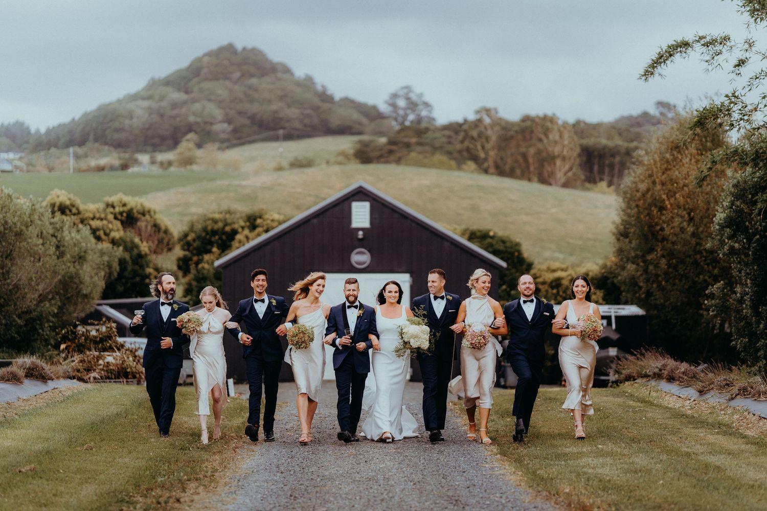 Bridal party walking down a path in front of a barn
