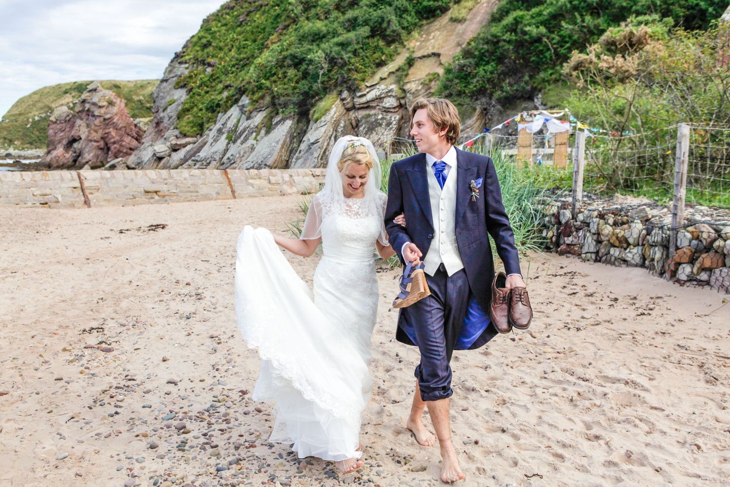 Couple walking along a scenic coastal beach path during their wedding.