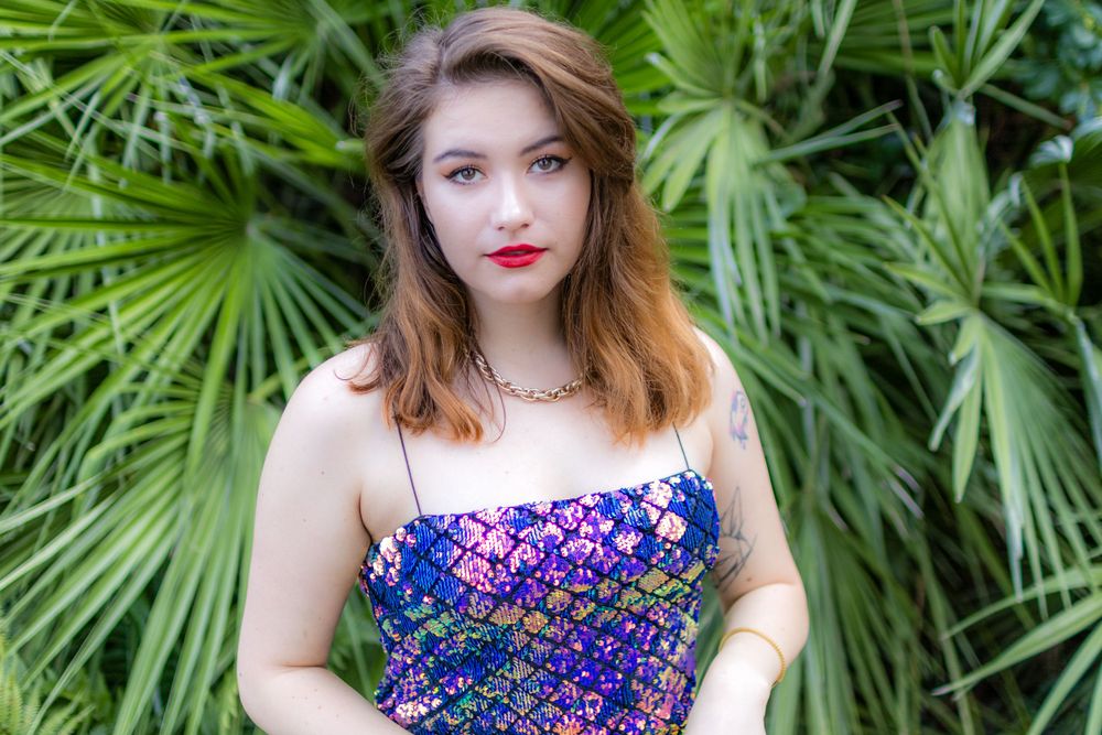 Beautiful model, Beata, posing in front of a green plant in Canary Wharf, wearing a purple dress