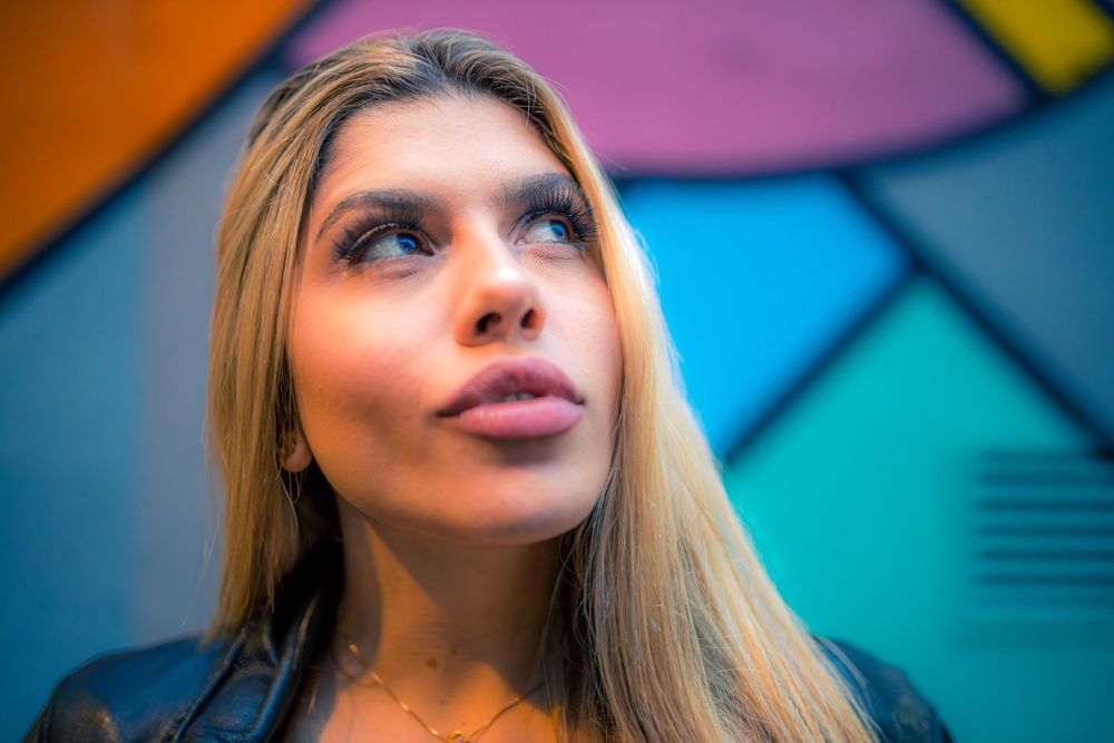 Pretty Brazilian model, Beatriz Sonnewend looking up to the right against a colourful wall background