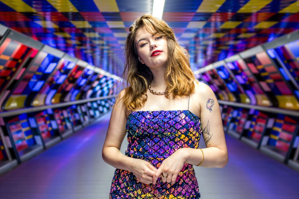 Gorgeous model Beata, wearing a sequinned purple dress in Canary Wharf colourful art walkway