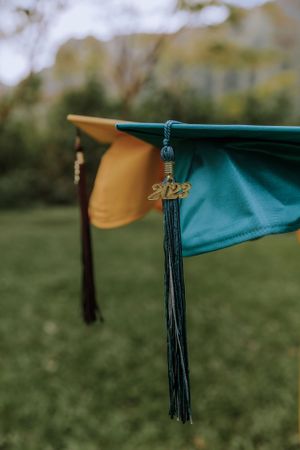 Detailed view of graduation cap tassels in contrasting yellow and teal colors.