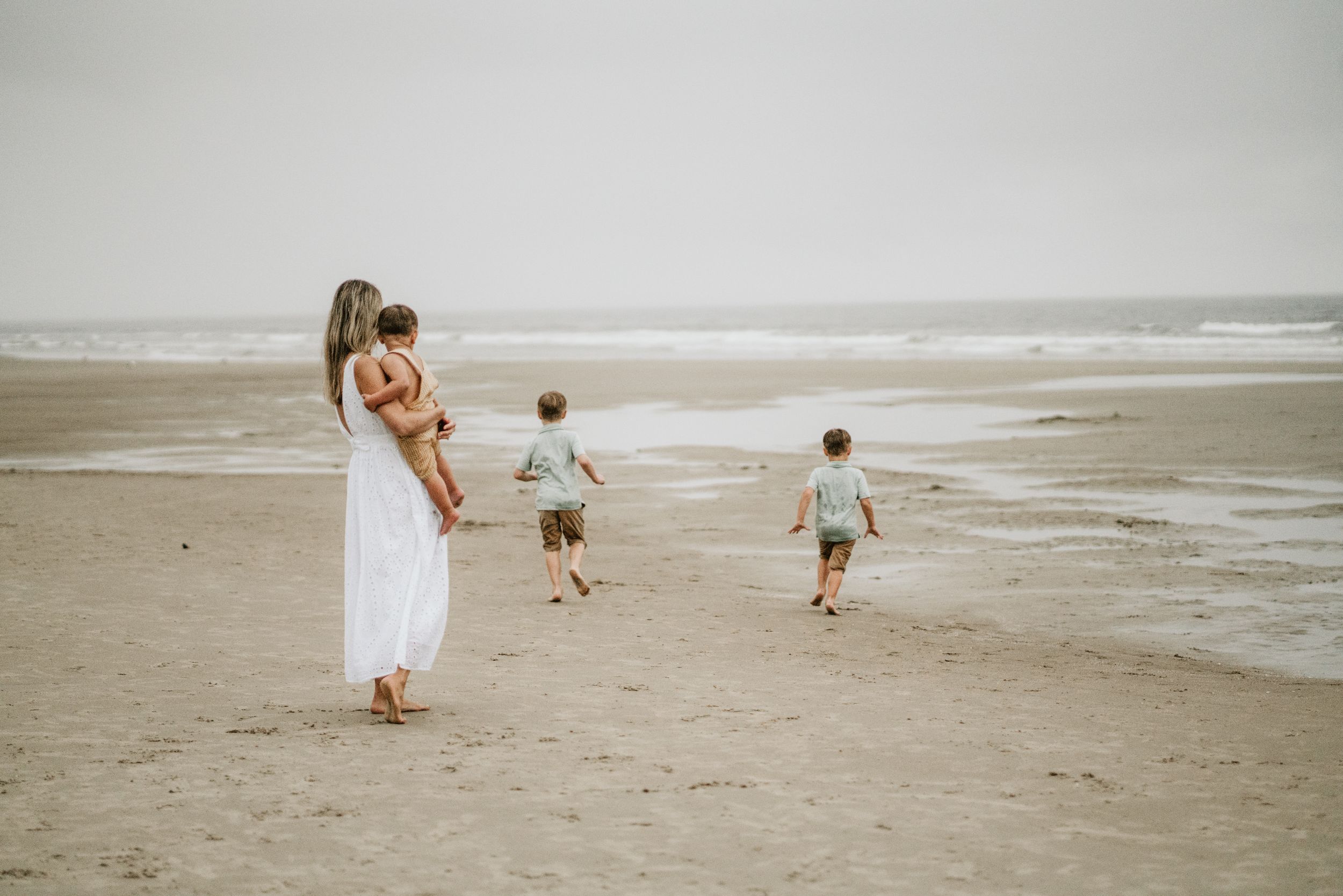 A peaceful scene of a parent and children walking along a misty beach at dusk.