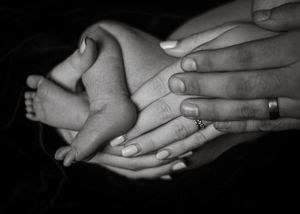 Black and white close-up of tiny baby feet cradled in adult hands.