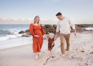 Family enjoying casual beach walk together at sunset among coastal rocks.