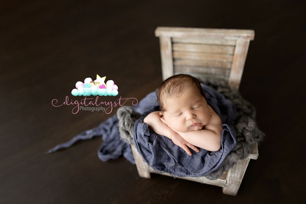 Peaceful newborn sleeping in rustic wooden crate with blue fabric.