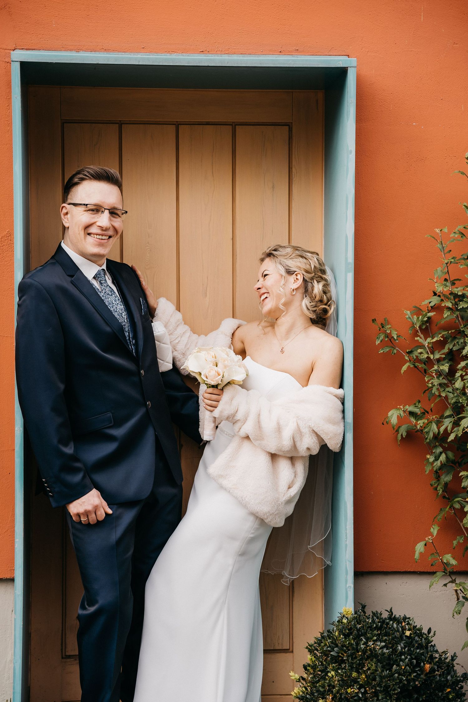 Wedding portraits against orange wall with turquoise trim doorways.