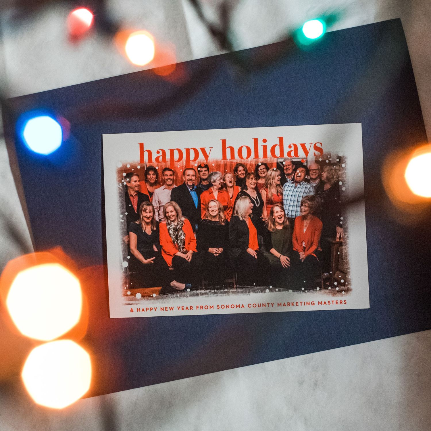Holiday card with group photo surrounded by colorful bokeh lights.