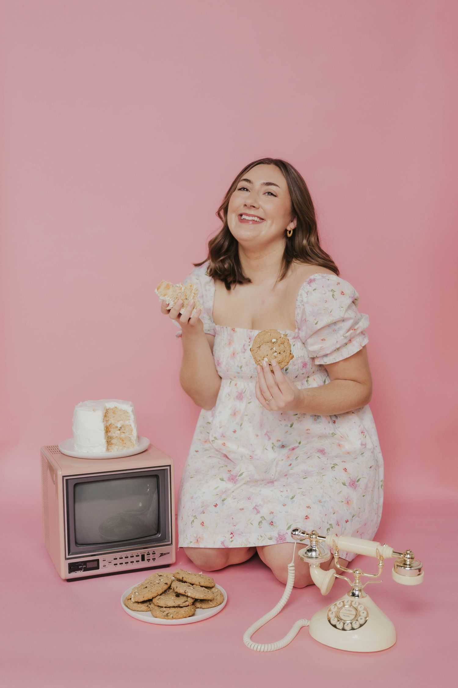 Retro themed photo with vintage TV, rotary phone, and cookies against pink backdrop.