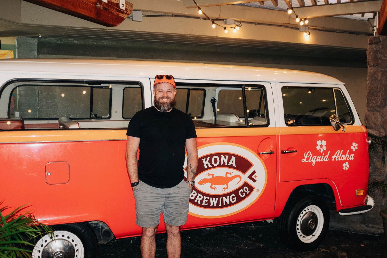 A white and red vintage VW bus with Kona Brewing Co branding parked indoors.