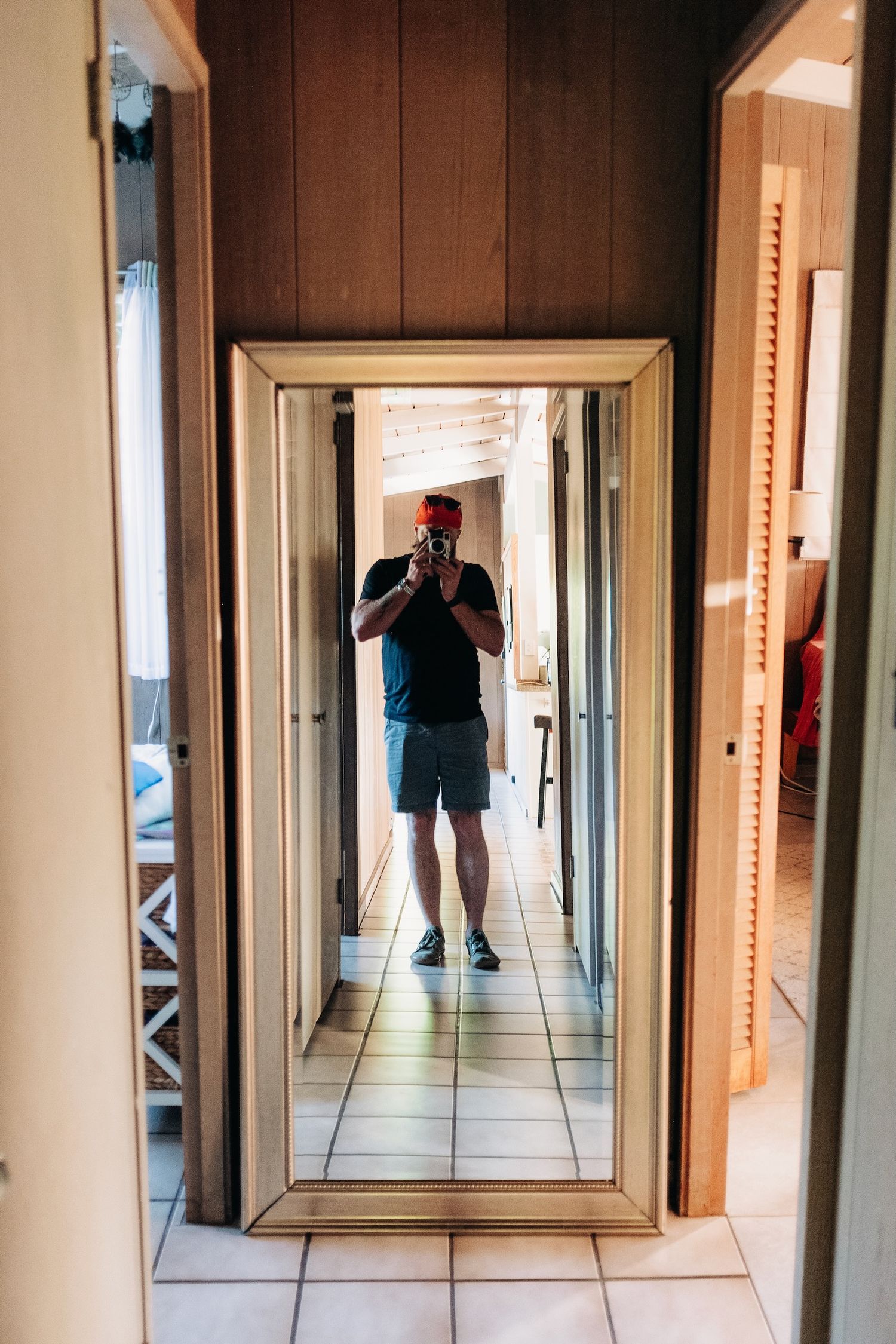 A mirror selfie showing someone in a red cap taking a photo in a hallway.