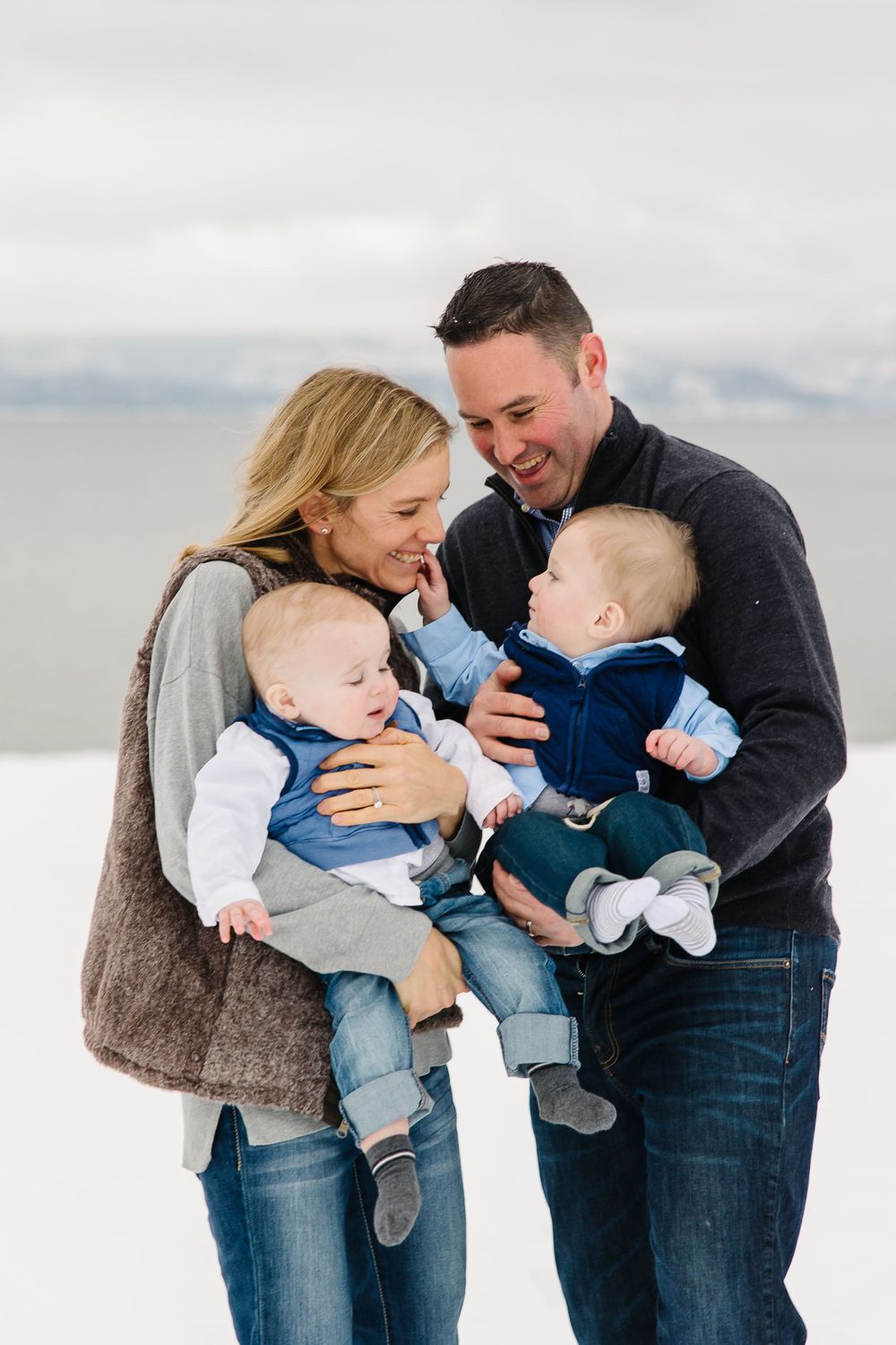 A loving moment between parents and their twin babies against a cloudy backdrop.