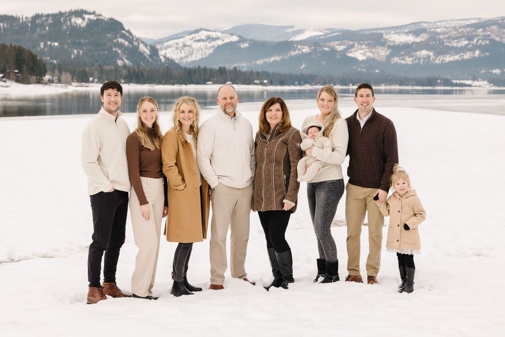 Winter family portrait with snow-covered mountains and lake in the background.